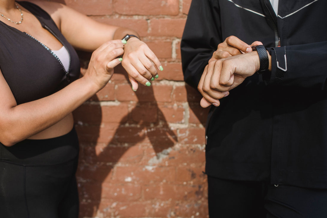 Two people checking fitness tracker watches outdoors